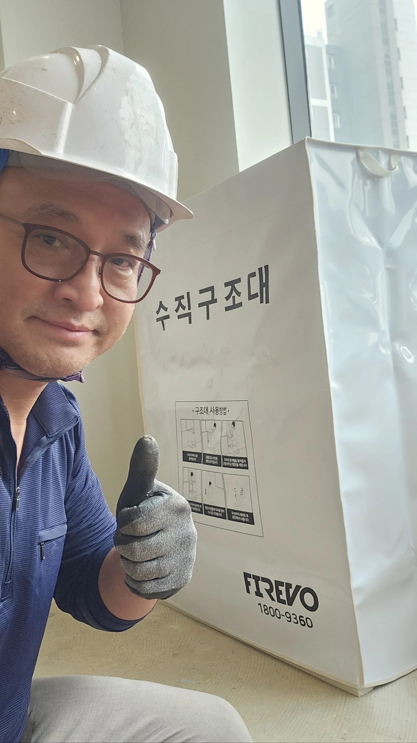 헬멧을 쓴 담당자가 수직구조대 글자가 적힌 흰 보관 박스 옆에 선 모습